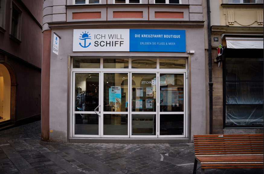 Eingangsansicht der „Ich will Schiff“-Filiale mit blauem Schild.